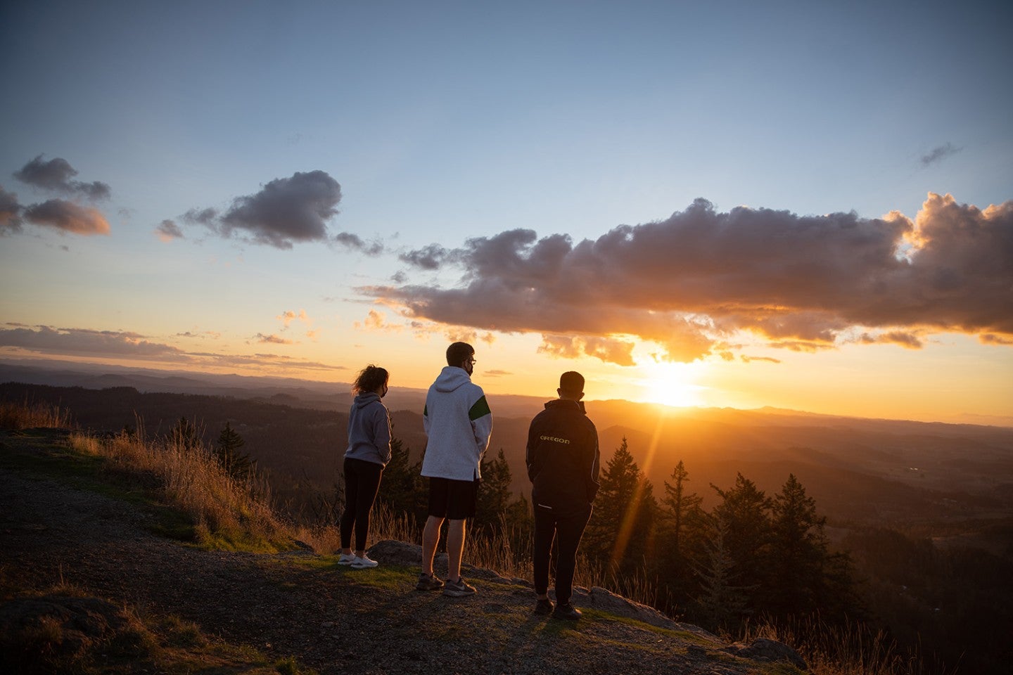 Trio of students watching the sunrise atop Spencer Butte in Eugene, Ӱԭ.